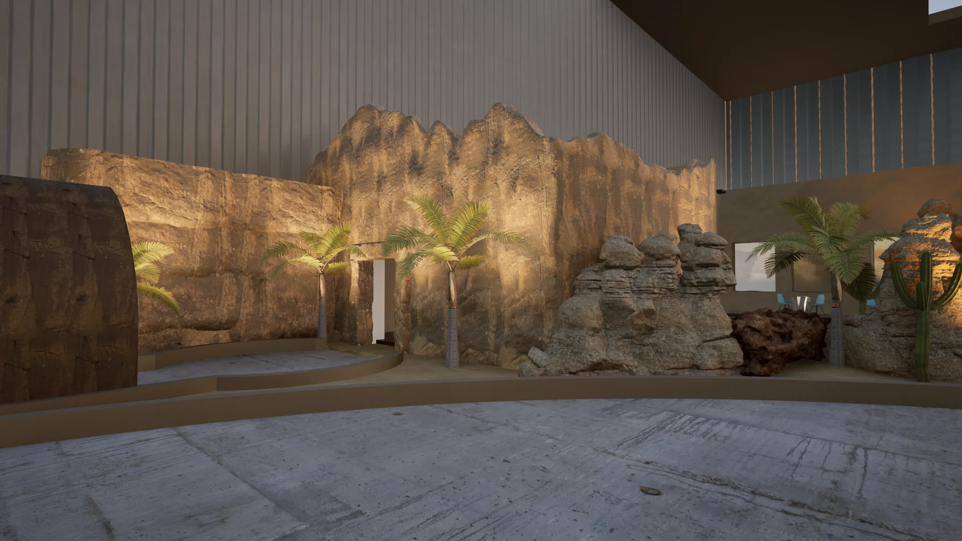 Outdoor desert landscape corner with illuminated rocky outcrops, fern plantings, a water feature and display panels — the open-air arena perimeter zone