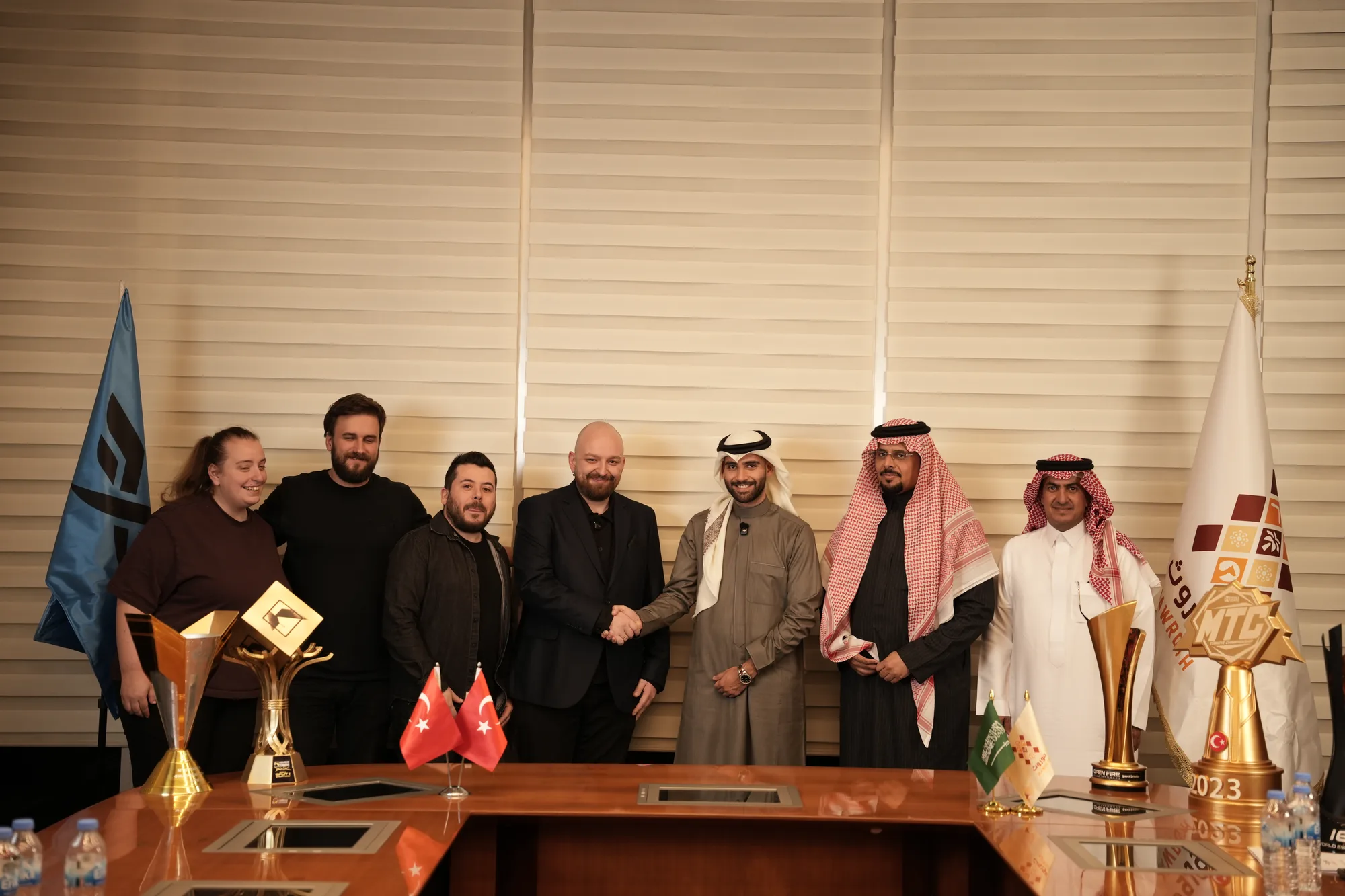 Mawroth and Fire Flux Esports delegations exchange handshake at partnership signing, esports championship trophies on desk