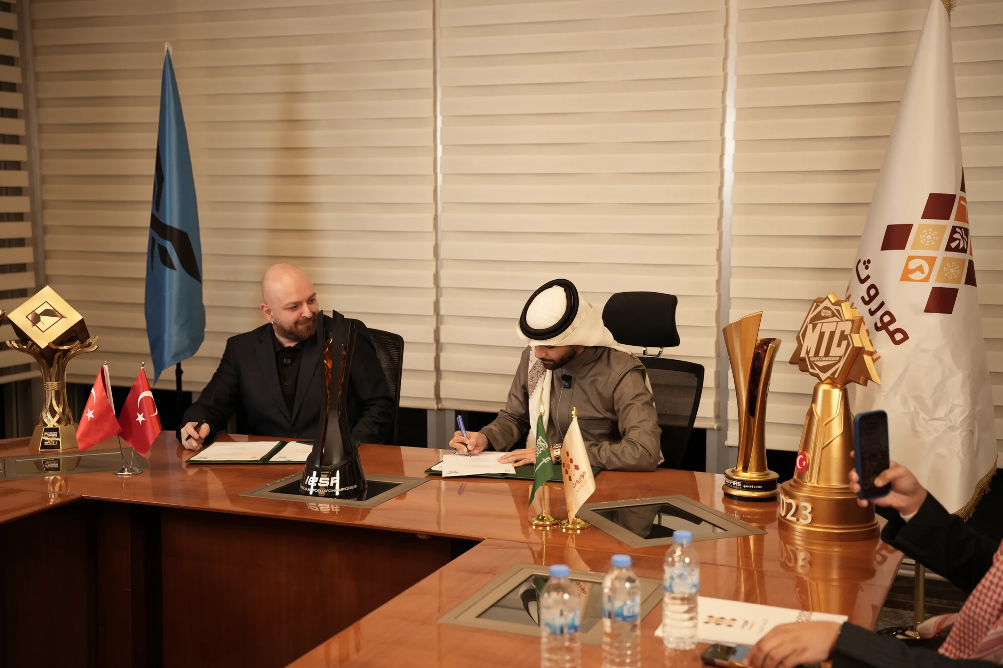 Two principals sign the strategic partnership agreement documents at the boardroom table