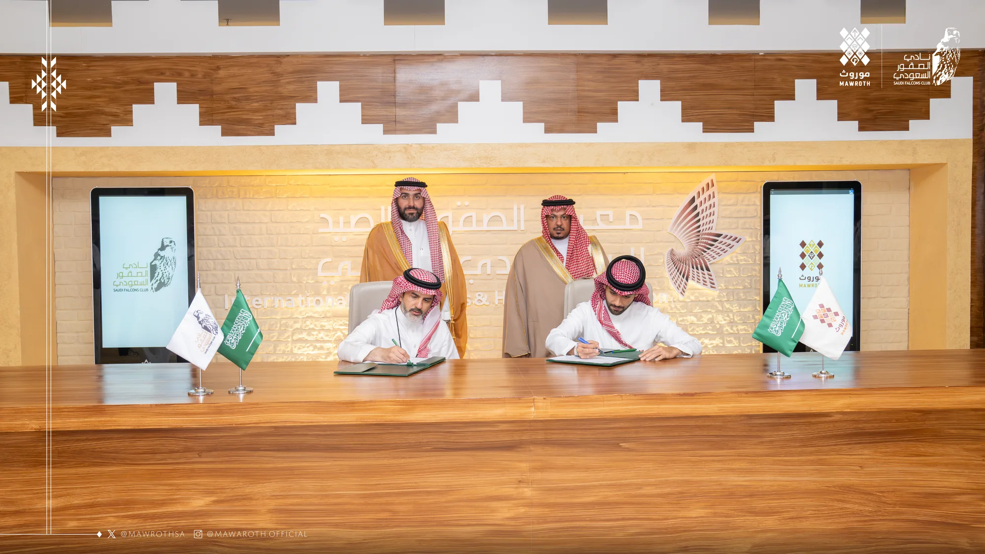 Closer view of the agreement signing moment — pens raised over the MOU documents with Mawroth and Saudi Falcons Club branding on display screens