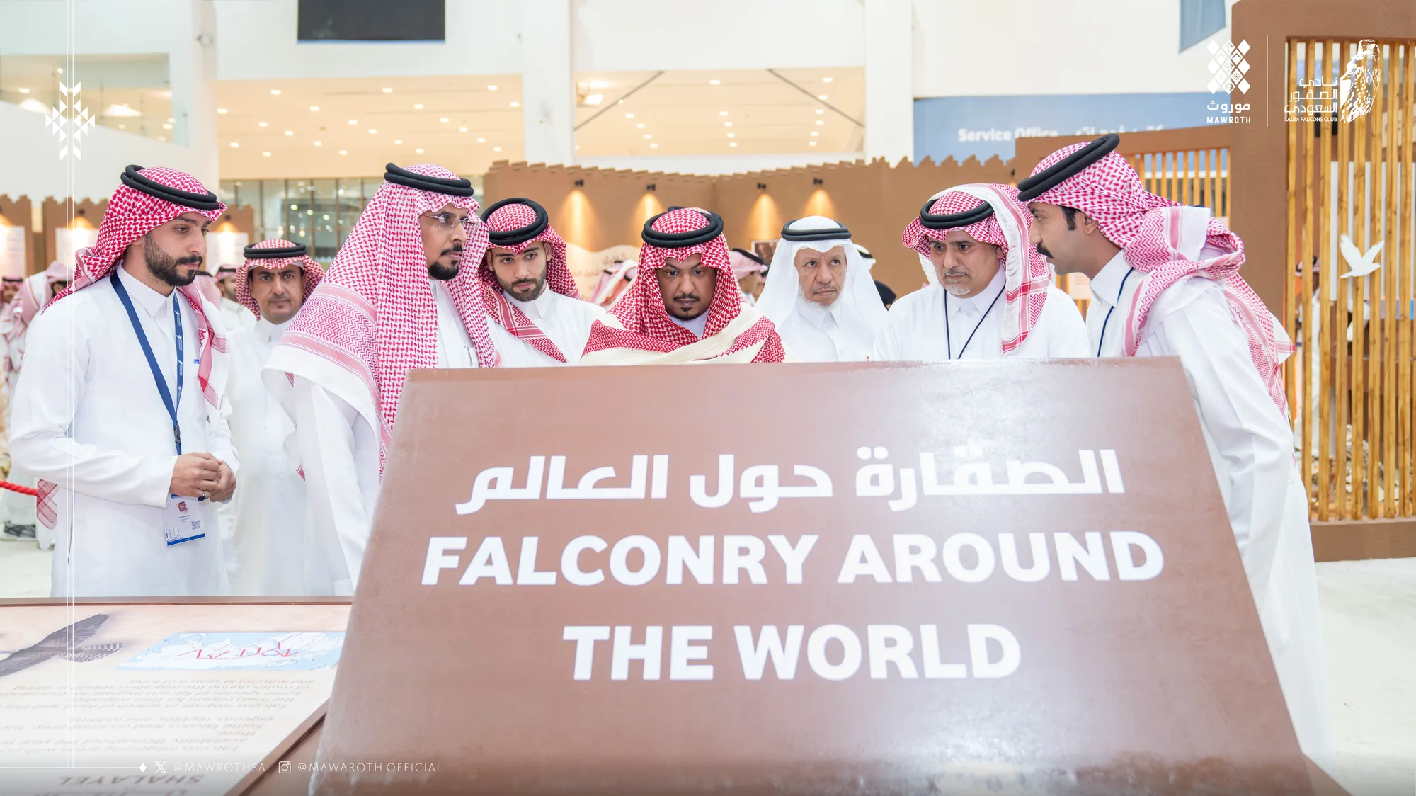 Delegation gathers around the 'Falconry Around the World' exhibit panel at the Saudi Falcons and Hunting Exhibition
