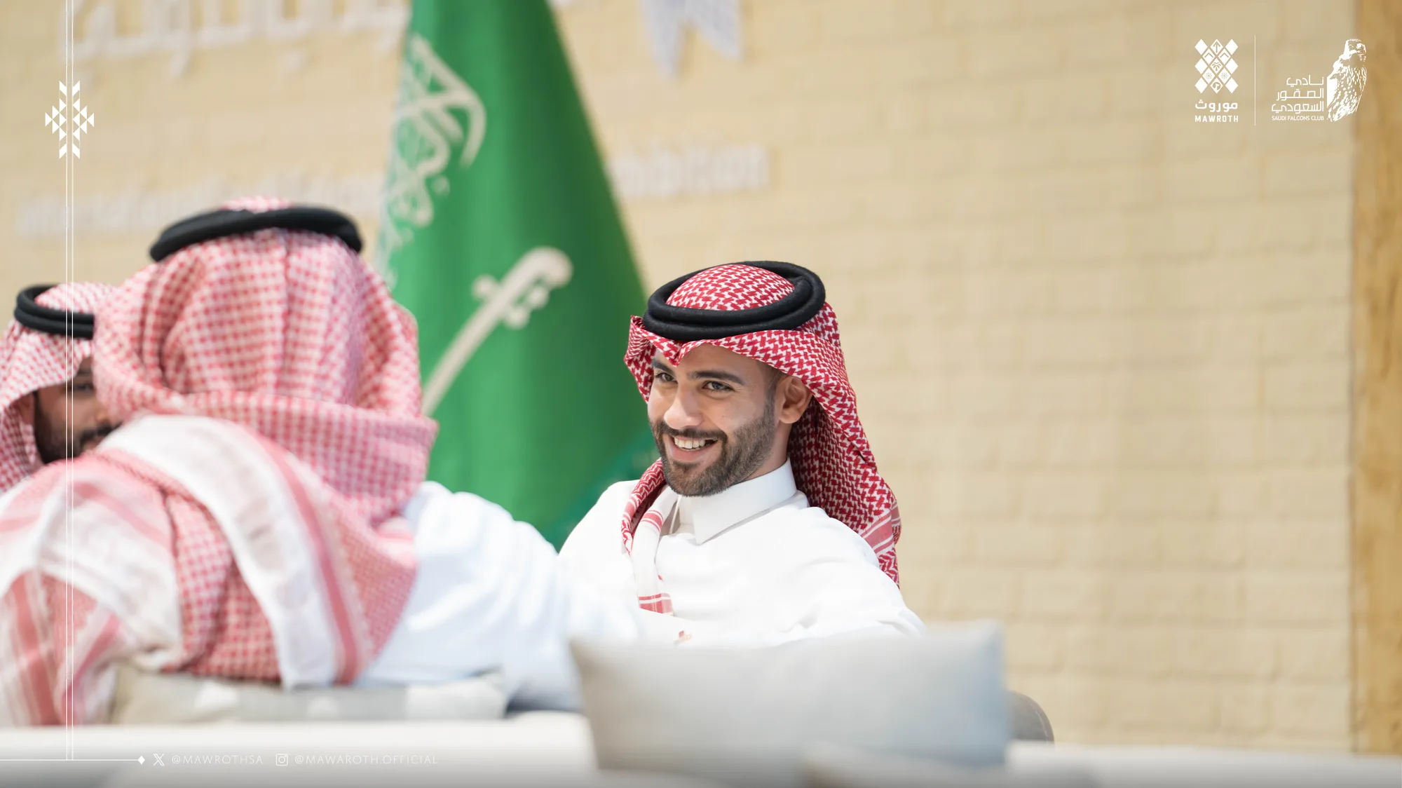 Mawroth founder in a relaxed moment at the signing table, laptop open and both organisation logos visible in the frame