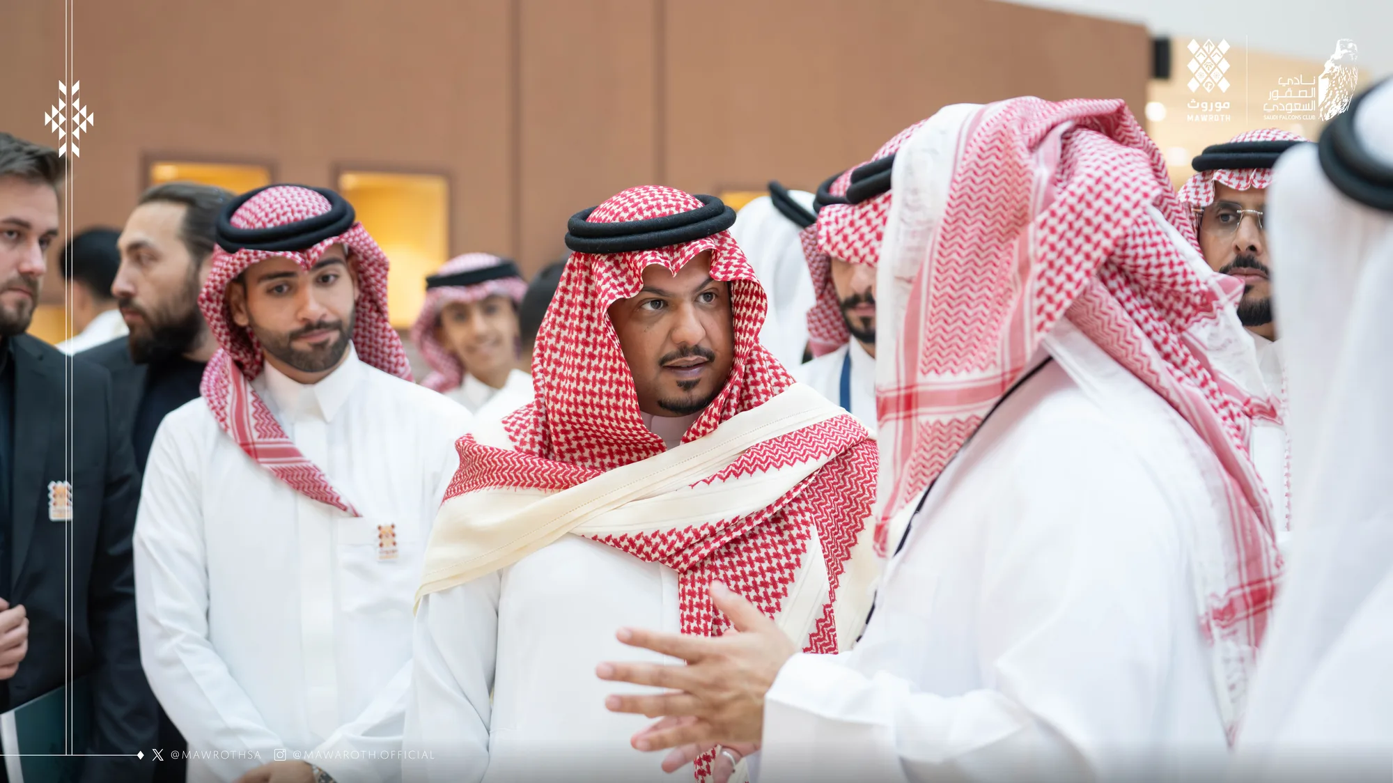 Mawroth founder in animated discussion with a senior official in the exhibition lobby, broader delegation in the background