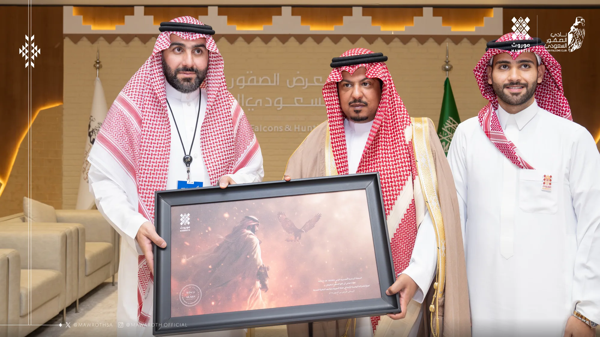 Official gift presentation — a framed Mawroth falcon artwork is handed to the Saudi Falcons Club representative