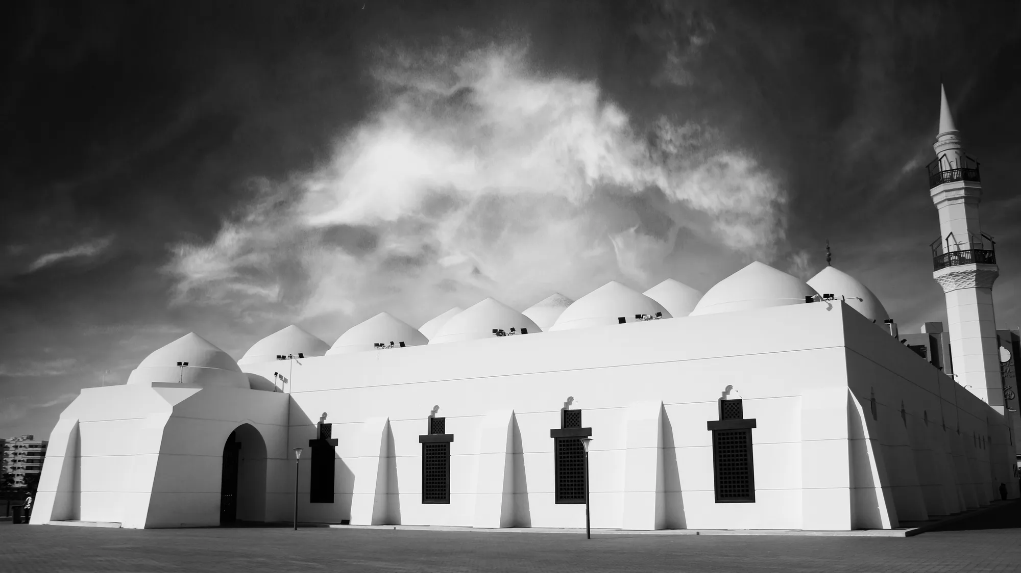 Jaffali Mosque, Jeddah — dramatic infrared monochrome showing a row of multi-dome roof and single minaret beneath stormy clouds
