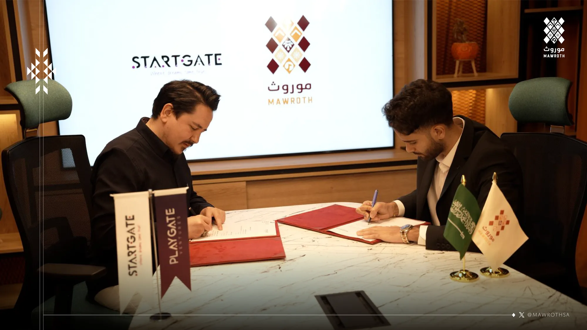 Mawroth and StartGate CEOs signing the strategic partnership agreement at the ceremony table, both logos projected behind them